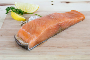 Salmon fillets fresh with lemon coriander salt and pepper on a wooden floor.