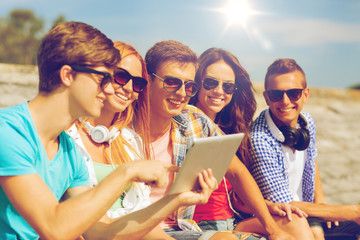 group of smiling friends with tablet pc outdoors