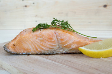 Salmon steak with lemon and coriander on a wooden floor.