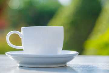 cup of coffee on  table in green garden