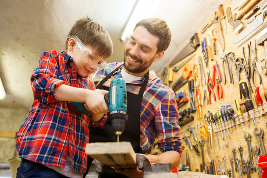 father and son with drill working at workshop