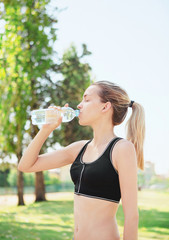 Ragazza beve acqua al parco sportiva