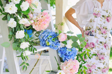 Florist woman at work decorating beautiful wedding arc outdoors, selective focus