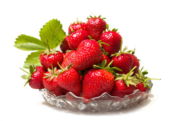 Ripe tasty strawberries in a glass vase with green leaves