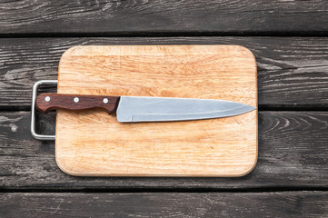 Steel knife on a cutting board  wooden background with