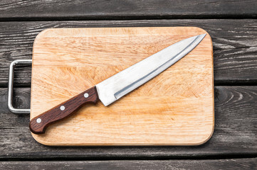 Steel knife on a cutting board  wooden background with