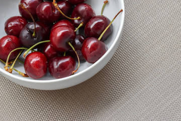 Group of red fresh cherries in white bowl. Top view of ripe healthy cherry