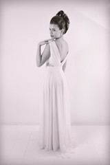 Fototapeta premium Black And White Studio Shot Of Sensual Elegant Woman With Classic Hairstyle Posing In Beautiful White Dress