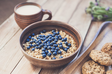 Obraz na płótnie Canvas Oatmeal porridge with blueberries, milk and cookies, healthy food concept