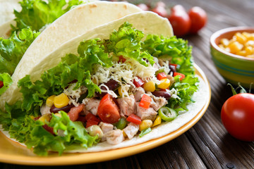 Mexican tacos with meat, beans, lettuce, corn, onion, tomato and 
