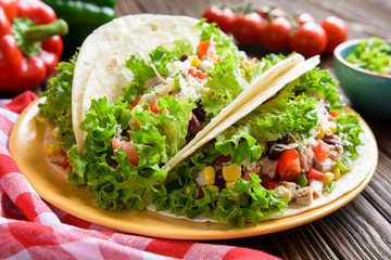 Mexican tacos with meat, beans, lettuce, corn, onion, tomato and 