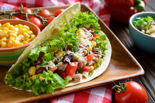 Mexican tacos with meat, beans, lettuce, corn, onion, tomato and 