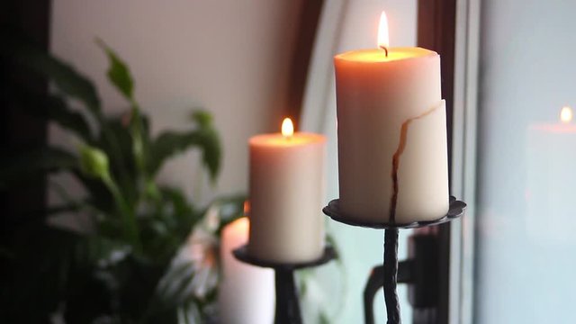 Burning candle on a candlestick cracked