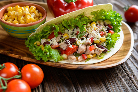 Mexican tacos with meat, beans, lettuce, corn, onion, tomato and cheese
