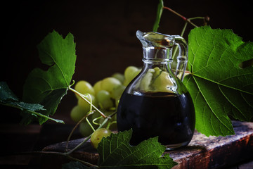 Balsamic vinegar in a glass jug, vintage wooden background, rust