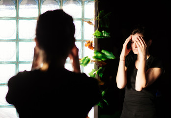 Woman having a headache in front of a mirror