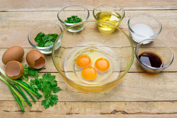 Raw eggs and ingredients on  wooden background. Vegetarian food, health or cooking concept.