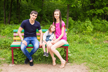 Fototapeta premium young family sitting on a bench in the summer park
