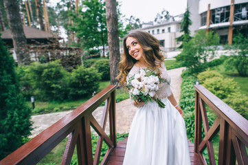 beautiful bride with white bouquet in park