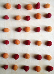 Flat lay of golden/orange & red raspberries on a wooden surface. Top view of berries laid in a pattern composition. Mobile photo. 