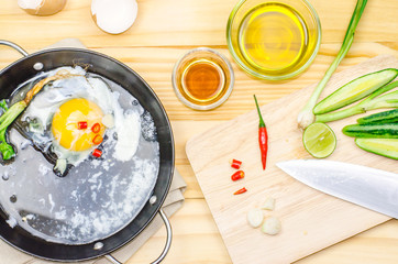 Chicken eggs in a frying pan over a vintage old wooden table. Ingredients for cooking. Rustic style. View from above.