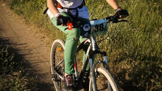 Girl on a downhill mountain bike rides down a dirt track in beautiful landscape.Mountain biker fast downhill sport race ride.Cyclist on pathway in mountain forest.Mountain bike. Cyclist rides a