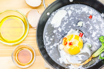 Chicken eggs in a frying pan over a vintage old wooden table. Ingredients for cooking. Rustic style. View from above.