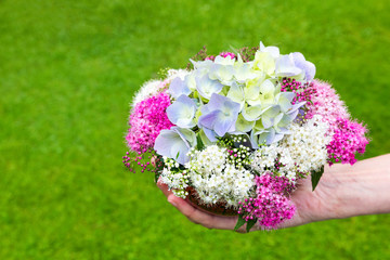 Hand giving bouquet of summer flowers in vase