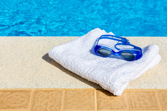 Swimming Goggles And Towel Near Swimming Pool