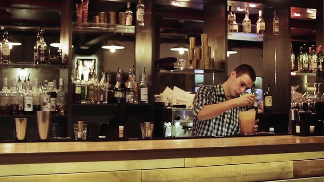 Young man working as a bartender in a nightclub bar