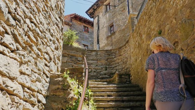 Woman tourist climbs the steps of the ancient town in Catalonia - Rupit. Popular among tourists place - the City of Witches