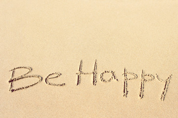 Be happy handwritten on the sandy beach