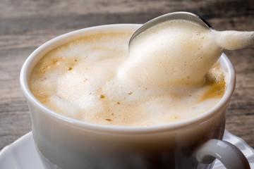 Cappuccino mit Milchschaum und Kaffeelöffel, Nahaufnahme.