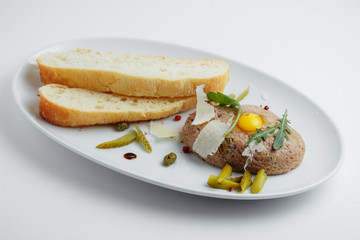 Meat cutlet with pickled cucumbers, fresh herbs and bread on a white plate
