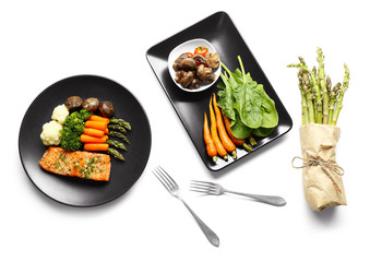 Tasty dish with baby carrots and salmon on black plate, top view