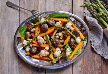 Vegetable salad with mushrooms and baby carrot on wooden table, top view