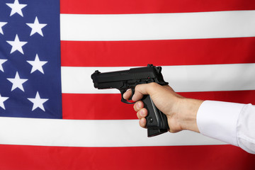 Man's hand holding gun on star and stripes background
