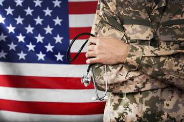 Army doctor holding stethoscope on American flag background