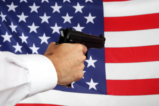 Man's hand holding gun on star and stripes background