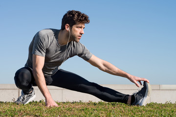 The athlete stretching leg in the grass