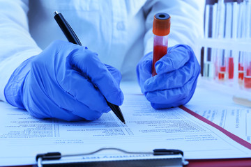 Doctor hands with blood sample on medical report