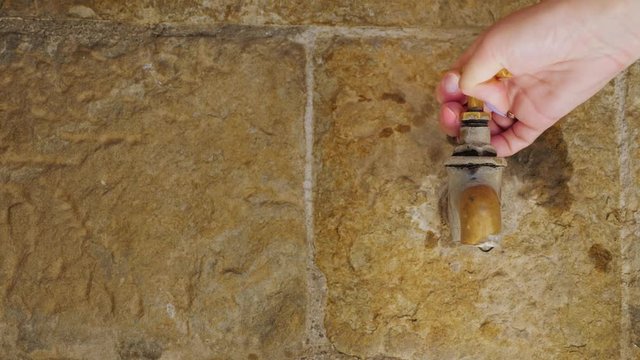 The water flows from the tap in the old stone wall. City Rupit Catalonia