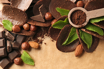 Composition of chocolate chips and spoon with cocoa powder on parchment background