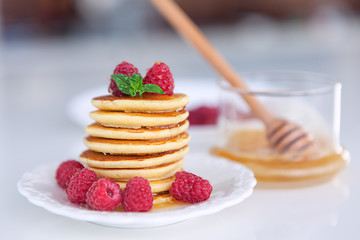 Pancakes with raspberry on white table