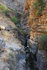 Горный маленький водопад среди оранжевых скал Тянь Шаня