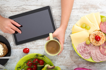 A woman's hand with food and tablet