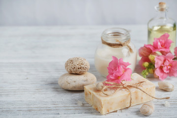 Fototapeta na wymiar Natural handmade soap, aromatic oil and flowers on white wooden