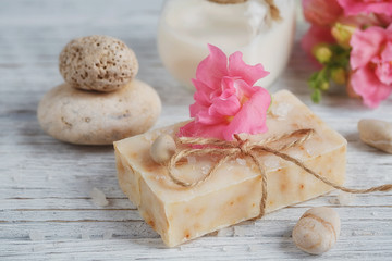 Obraz na płótnie Canvas Natural handmade soap, aromatic oil and flowers on white wooden