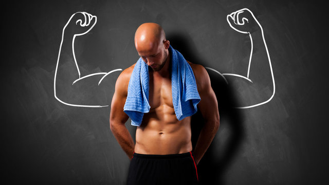 Muskulöser Mann vor einer Kreidetafel mit Kraftgeste