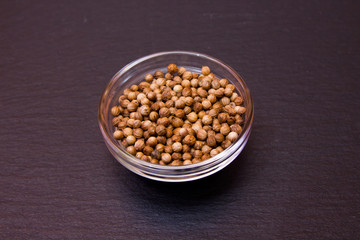 Coriander seeds of bowl on a slate floor